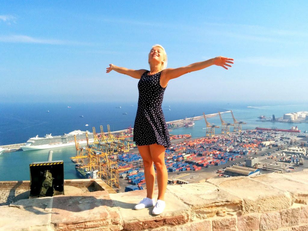 a_blonde_girl_standing_on_an_edge_of_barcelonas_port