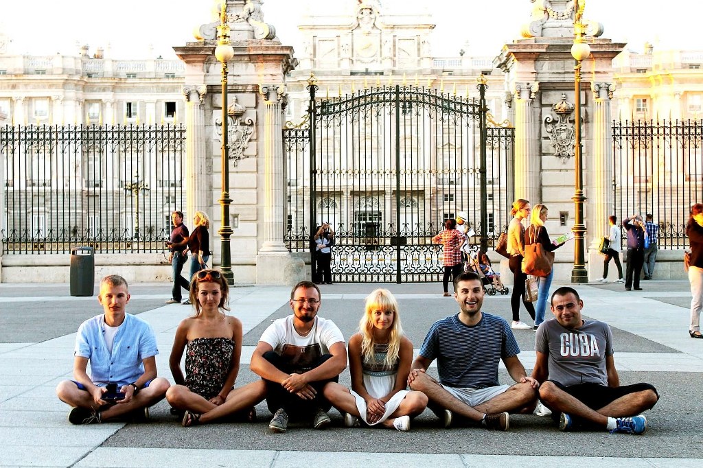 a_group_of_friends_sitting_on_a_ground_in_front_of_the_palace_in_madrid