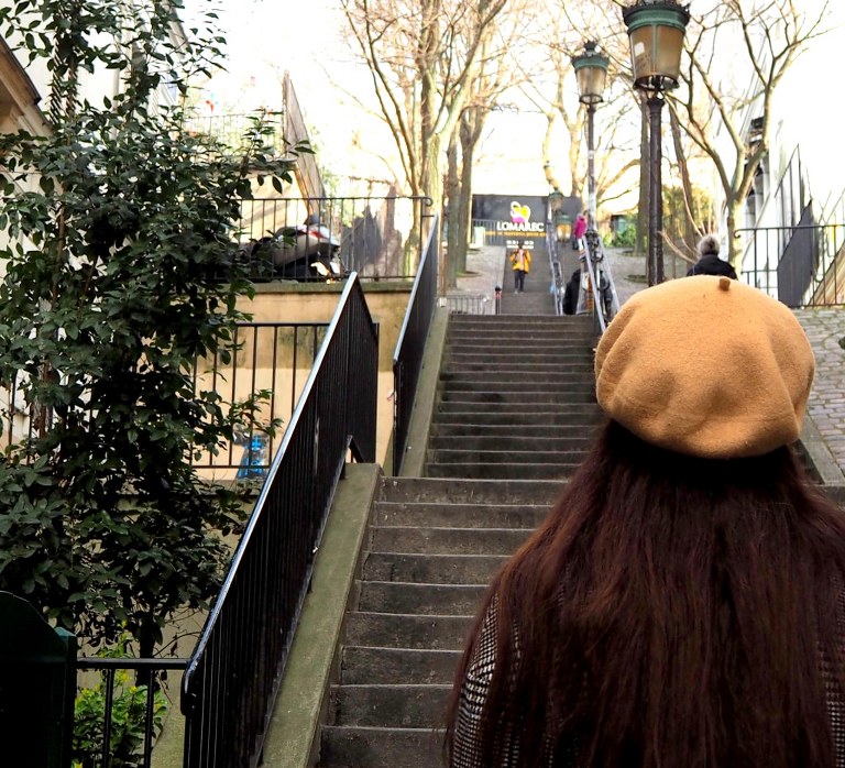 a_Dark_hair_girl_in_a_paris_style_hat_standing_in_front_of_a_high_stairs