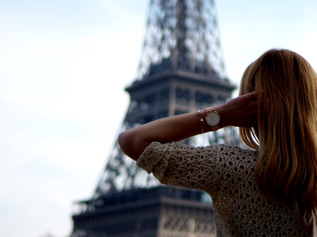 a_blond_girl_standing_in_front_of_the_eiffel_tower