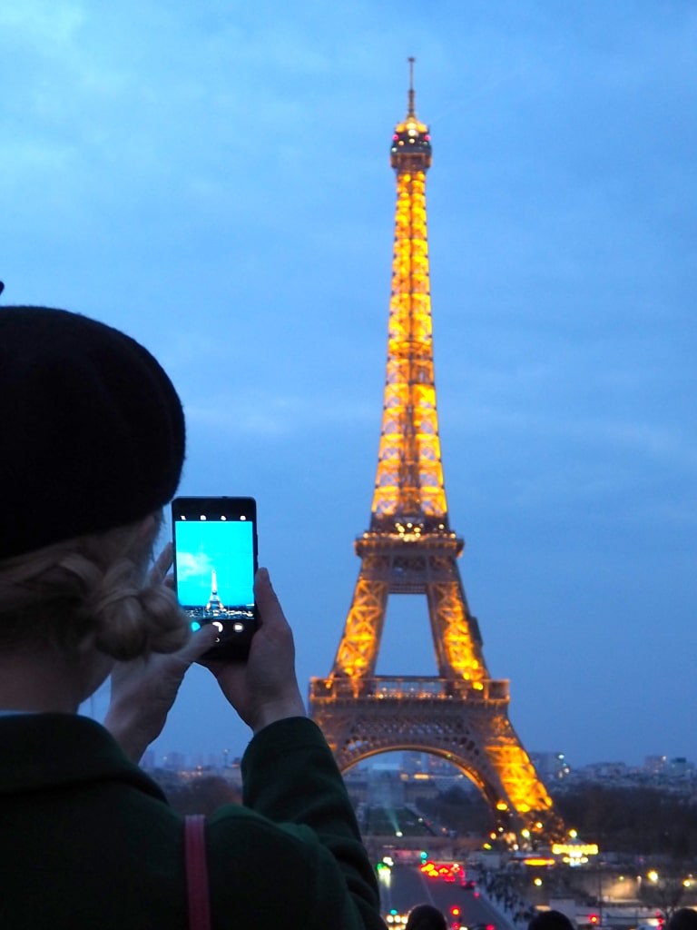 a_girl_taking_photo_of_the_eiffel_tower_in_nightlight